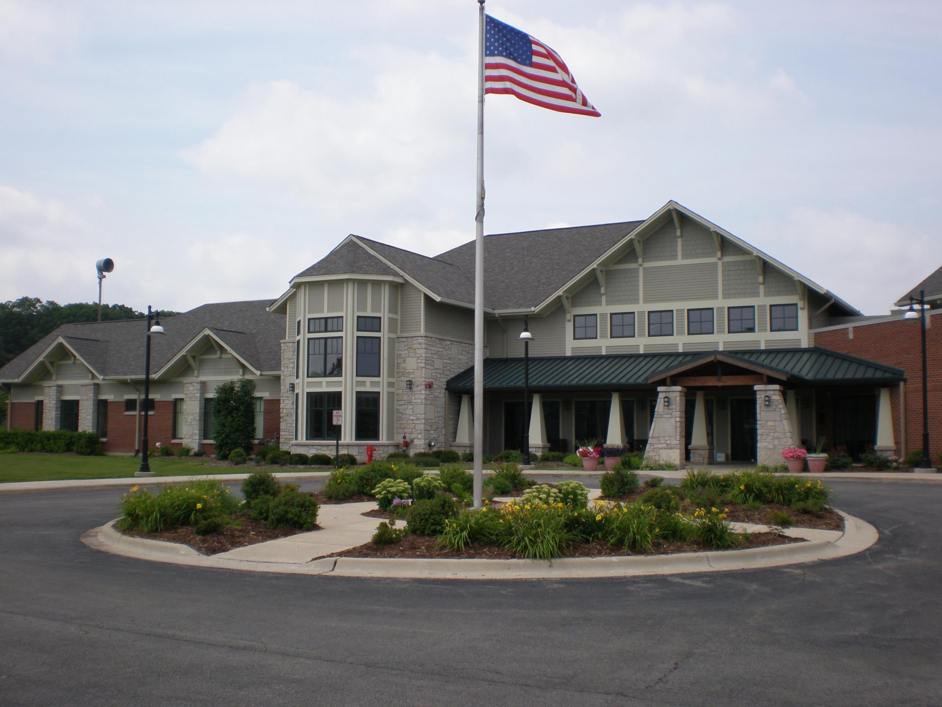American flag with flowers around it in front of the Hanover Township Senior Center building on a cloudy day.